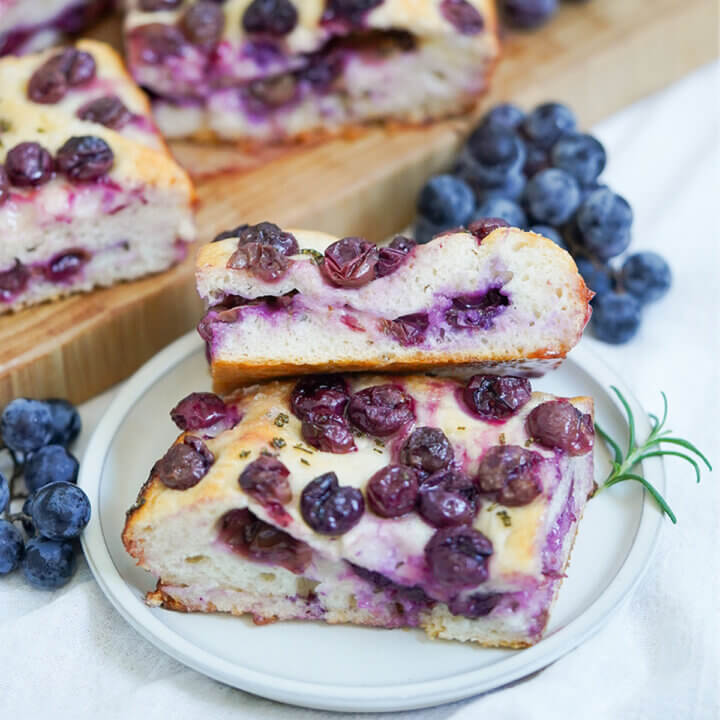 slices of Schiacciata all’uva grape focaccia on plate with grapes behind.