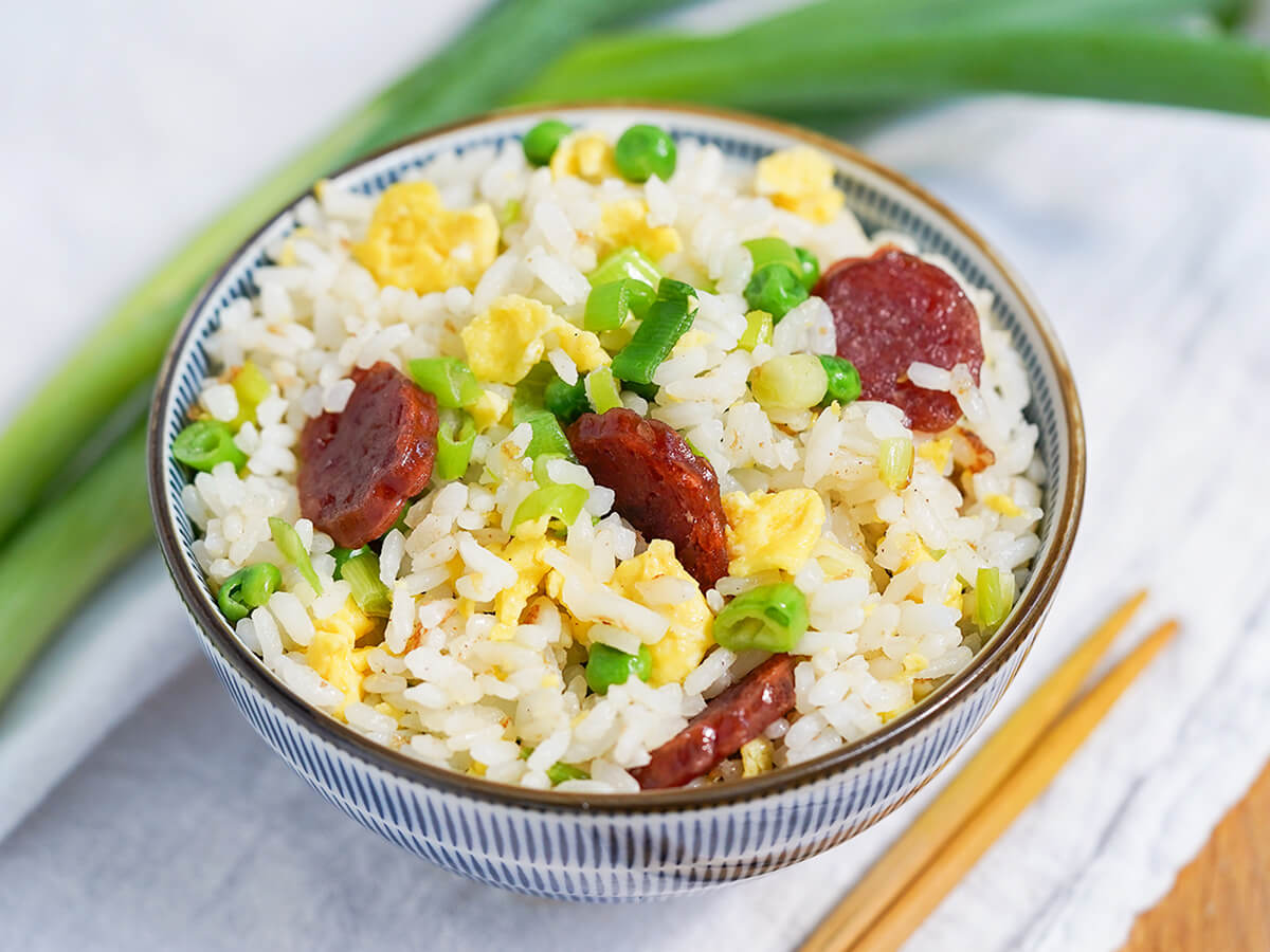 bowl of Taiwanese fried rice side view of bowl of Taiwanese fried rice with scallions behind bowl.