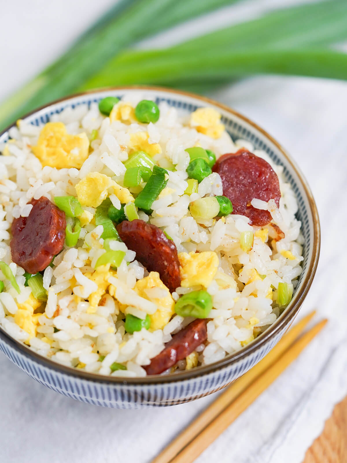 view of a bowl of Taiwanese fried rice from side with tips of chopsticks showing below bowl.