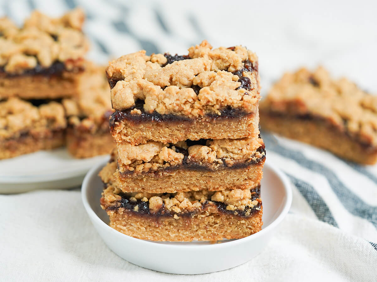 stack of peanut butter and jelly bars with more blurred in background.