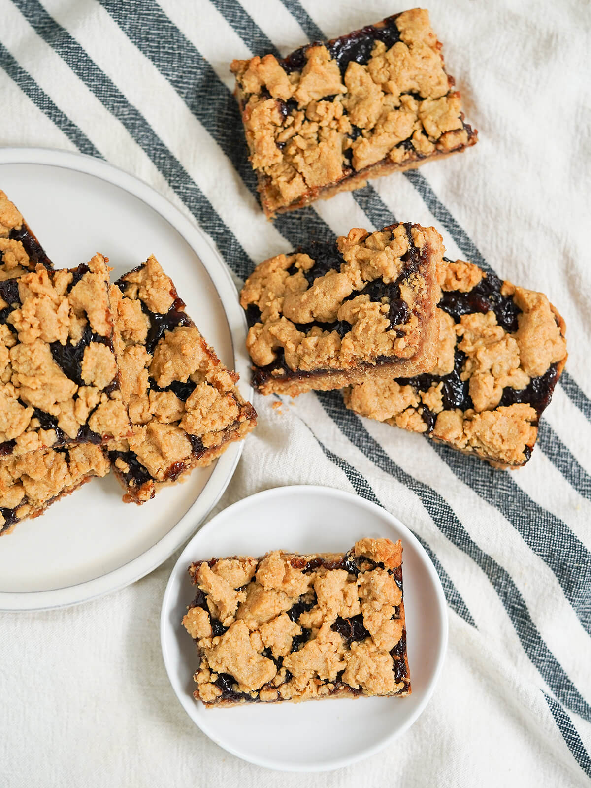 overhead view of slices of peanut butter and jelly bars on plates and cloth.