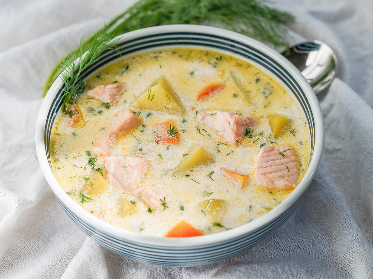 side view of bowl of Finnish salmon soup with tip of spoon showing behind.