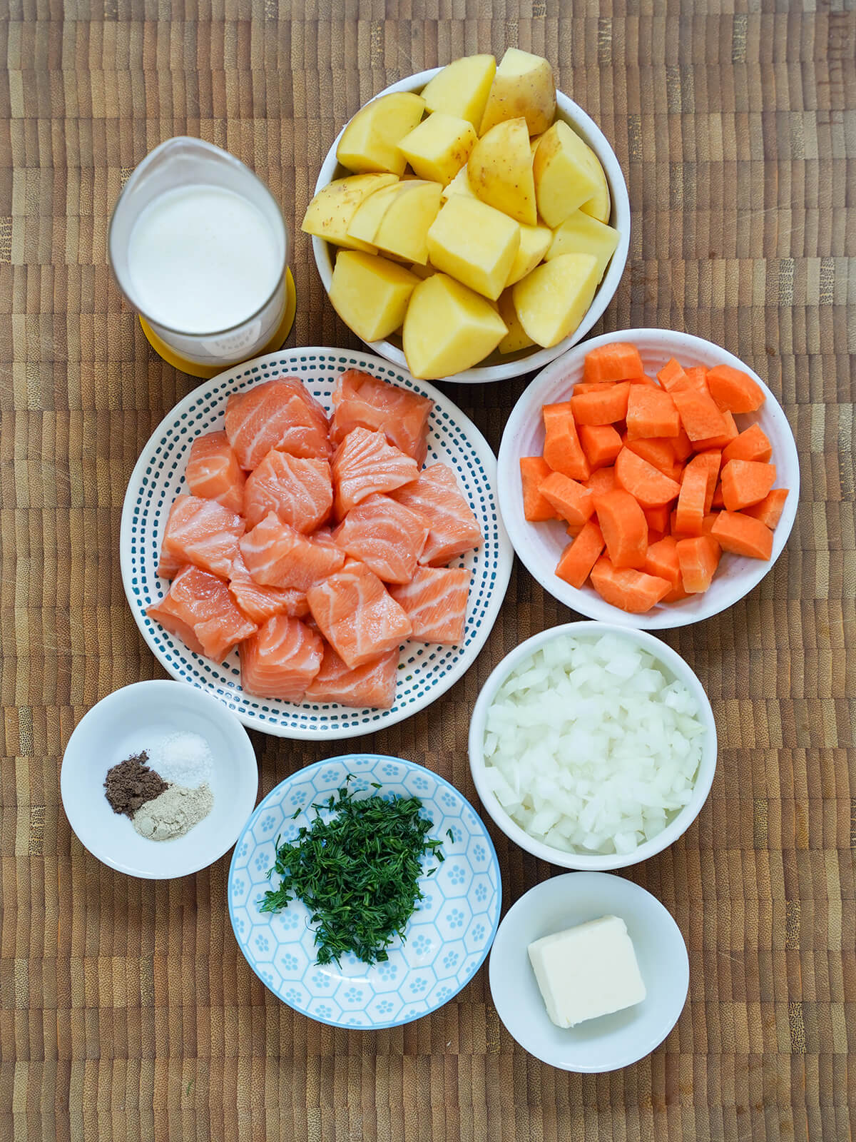 dishes of chopped salmon, potatoes, carrots, onion and dill with small dish with butter, spices and measure of cream.