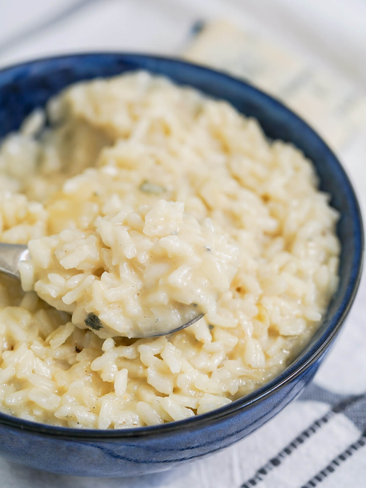 This gorgonzola risotto is easy to make and full of fantastic flavor. Creamy and comforting, it's great on it's own or served as a side. spoon of gorgonzola risotto sitting on top of bowl full of more.